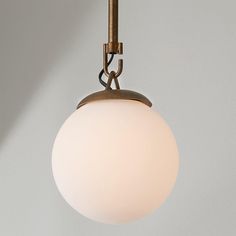 a white ball hanging from a light fixture on a gray wall with a metal hook