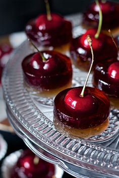 some cherries are sitting on a glass platter