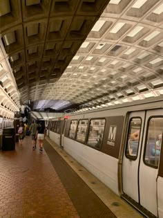 a subway train stopped at the station with people walking on the platform next to it