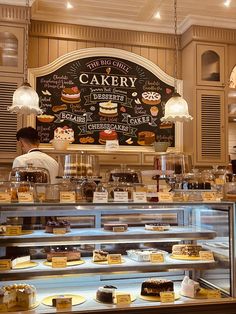 a bakery filled with lots of different types of cakes and pastries on display in front of a chalk board