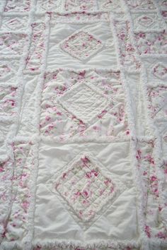 a white quilt with pink flowers on it