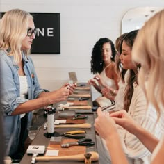 a group of women standing around a table with different types of tools on it,