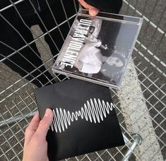 a person holding up a cd in front of a shopping cart with the cover open