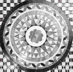 a black and white photo of a flower on a tile floor in the shape of a circle