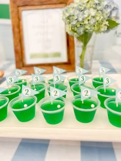 green cups with numbered numbers on them sitting on a table next to a framed photo