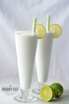 two glasses filled with white liquid and limes