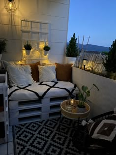 a couch made out of wooden pallets sitting on top of a tiled floor next to a potted plant