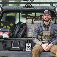 a man sitting in the back of a truck with his luggage on it's trunk