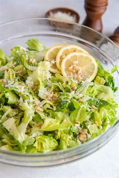 a glass bowl filled with lettuce and lemon slices