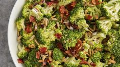 a white bowl filled with broccoli and nuts on top of a gray table