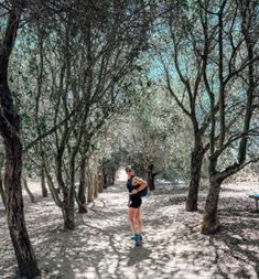 a woman running through the woods on a sunny day