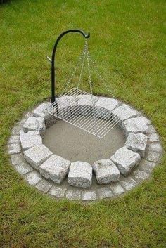 an outdoor fire pit made out of rocks and chains with a grill in the middle