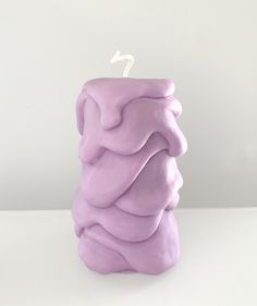 a purple candle that is sitting on a white counter top with the light turned on