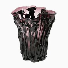 a black and pink glass vase sitting on top of a white table next to a wall