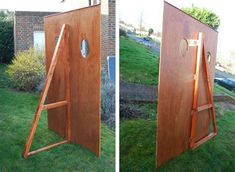 an open wooden door on the grass next to a brick building with a ladder in it