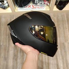 a person holding up a black motorcycle helmet