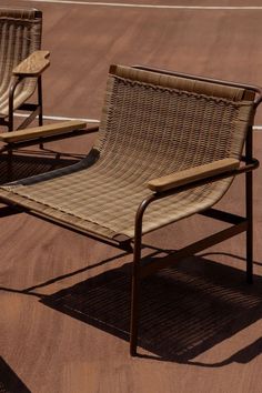 two chairs sitting on top of a tennis court next to each other in the sun