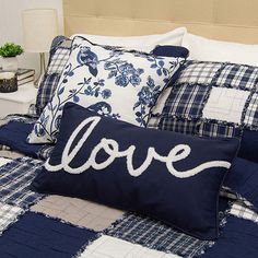 a bed with blue and white quilted bedspread that says love on it