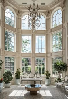 a living room filled with lots of windows next to a chandelier hanging from the ceiling