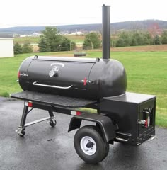 a black bbq grill sitting on top of a parking lot next to a field