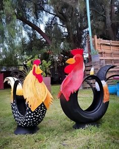 two rooster sculptures sitting in the grass next to each other on top of tire tires