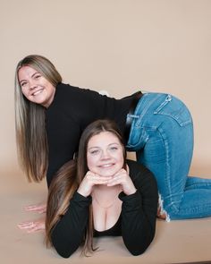 two women are laying on the floor posing for a photo