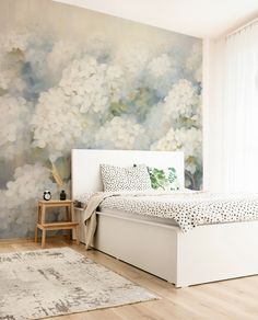 a white bed sitting in a bedroom next to a painting on the wall behind it