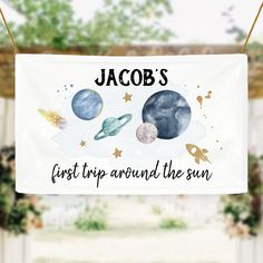 a white banner hanging from the side of a building with planets and stars on it that says, jacobs first trip around the sun