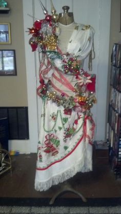 a white dress with red and gold decorations hanging from it's front rack in a living room