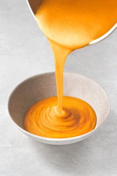 orange sauce being poured into a white bowl