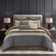 a bed with grey and brown comforters in a room next to two lamps on a table