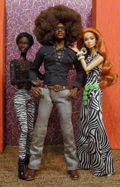 two dolls standing next to each other in front of a wall with zebra print on it