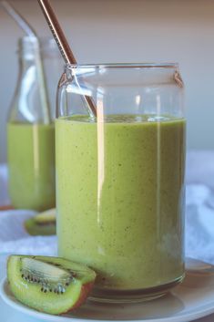 a glass jar filled with green smoothie next to sliced kiwi on a plate