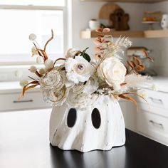 a white vase filled with flowers on top of a table