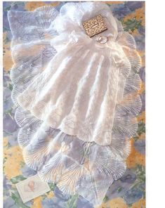 an image of a baby's white dress and bonnet on a quilted surface