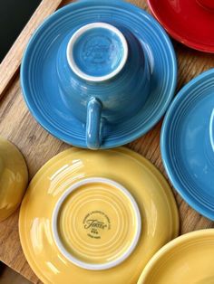 four different colored plates sitting on top of a wooden table next to an orange bowl