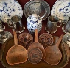 an assortment of antique silverware on display in a wooden case with other items around it