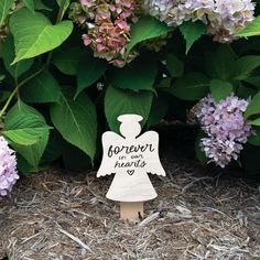 a small wooden angel standing in front of some flowers