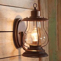 an old fashioned light hanging on the side of a wooden wall next to a door