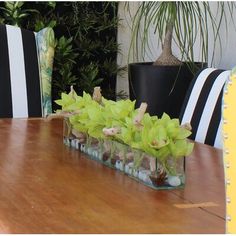 a wooden table topped with vases filled with green flowers and rocks sitting on top of it