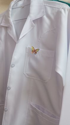 a white shirt with a butterfly on the chest and two small patches in the pocket