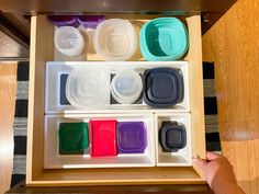 the drawer is filled with plastic containers and lids