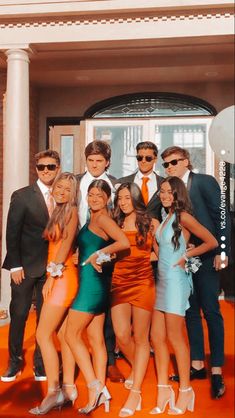 a group of people standing next to each other in front of a building with an orange carpet