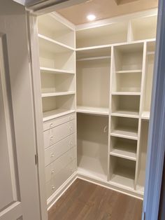 an empty walk in closet with white shelving