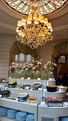 a buffet area with blue plates and bowls on the counter under a chandelier