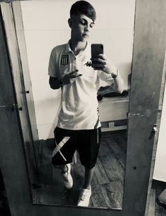 a man taking a selfie in front of a mirror while wearing shorts and a t - shirt