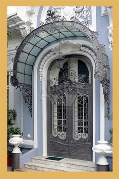 the front door of a blue house with white trim and ornate iron work on it