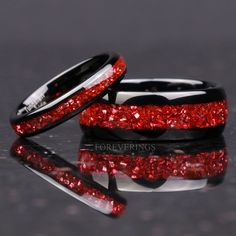 two wedding bands with red glitter in the middle and one black band on each side