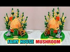 two small houses made out of paper on top of a green plate with flowers and plants