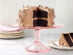 a chocolate cake sitting on top of a table next to a plate with a slice missing